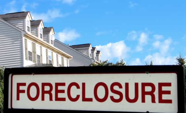 Picture of a foreclosure sign with a row of houses in the background in riverside, ca